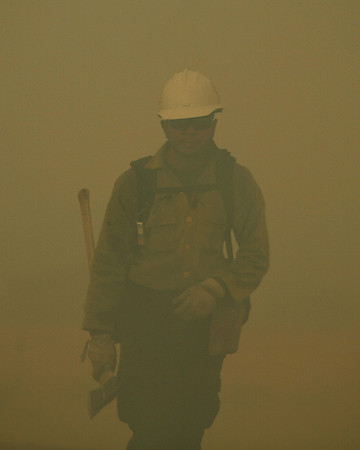 Obscured by smoke a firefighter moves along the line on the Wallow Fire