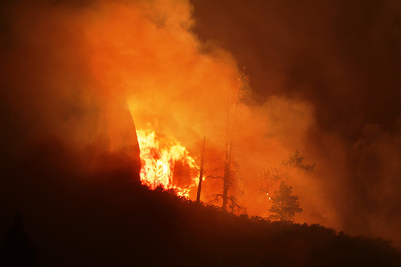 Fire reflects off of the larger cliffs behind it at the mouth of West Fork