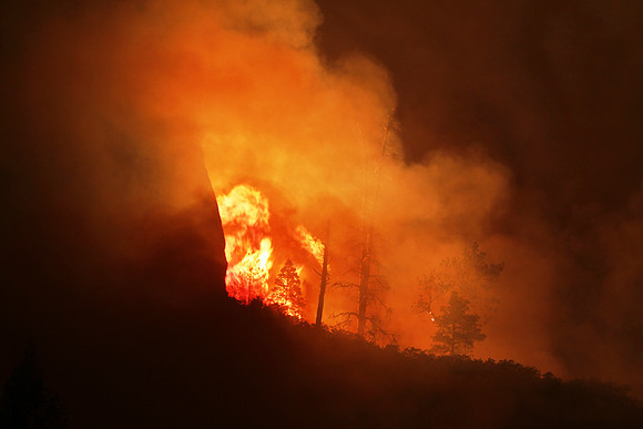 Fire reflects off of the larger cliffs behind it at the mouth of West Fork